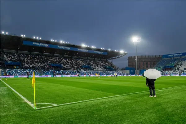 Stadio Mapei di notte con una persona a bordo campo con un ombrello. Il campo è illuminato dal proiettore sportivo 'Altis' di Thorn