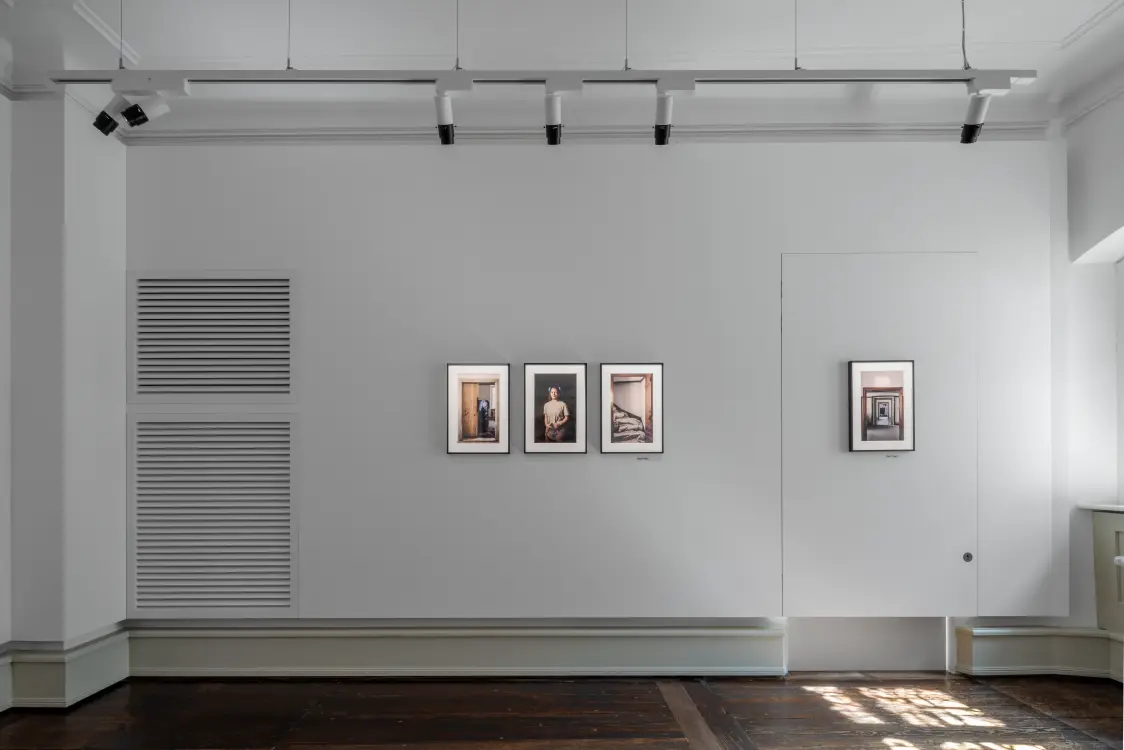 Minimalistische tentoonstellingsruimte in het Stadtmuseum Cavazzen in Lindau met drie ingelijste foto's aan de witte muur en een moderne lichtinstallatie aan het plafond.