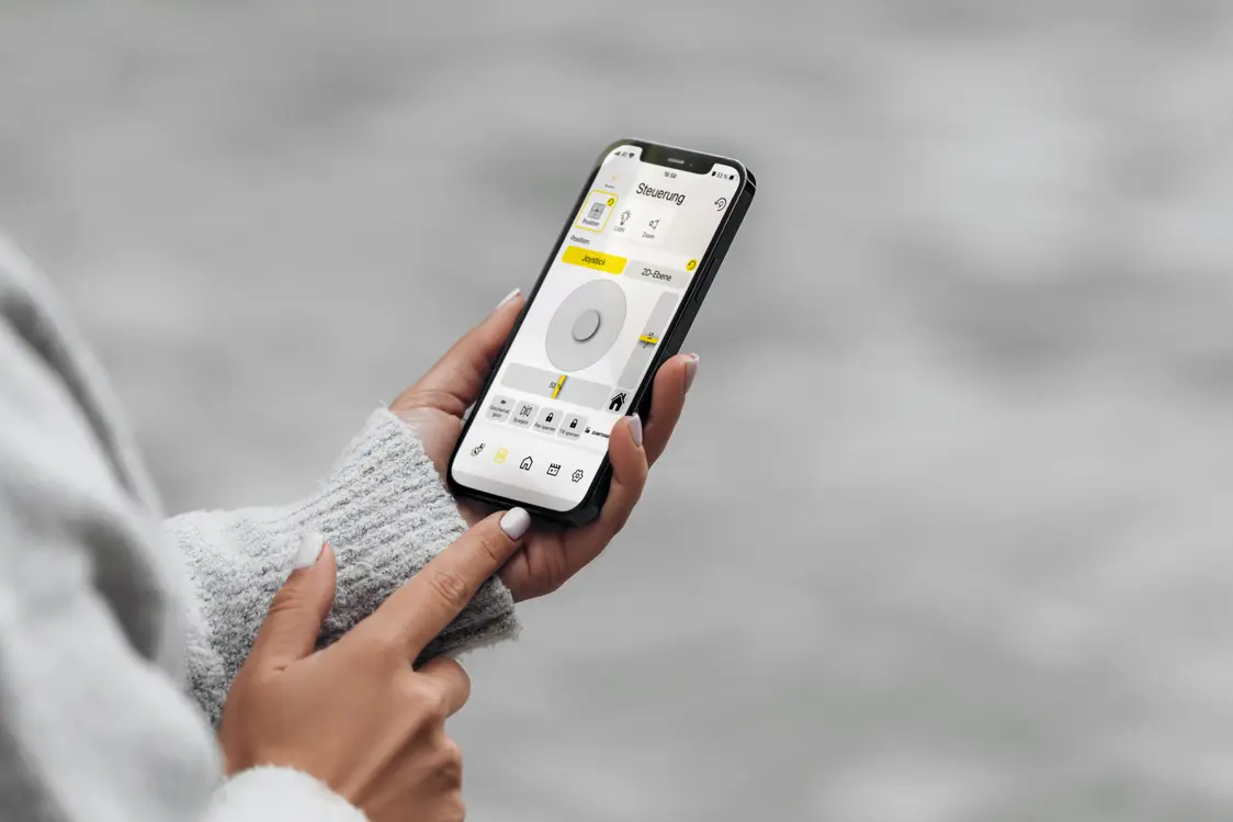 Eine Person steuert das AGILIO Beleuchtungssystem über einen Smartphone-Bildschirm, der Steuerungsoptionen zeigt.