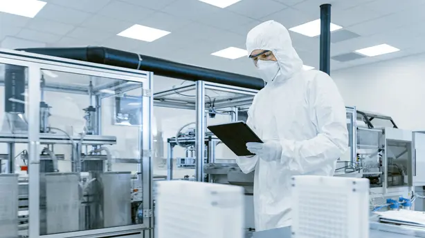 A sterile room in a pharmaceutical facility with a person in protective clothing. In the background, the cleanroom luminaires from Zumtobel are visible.