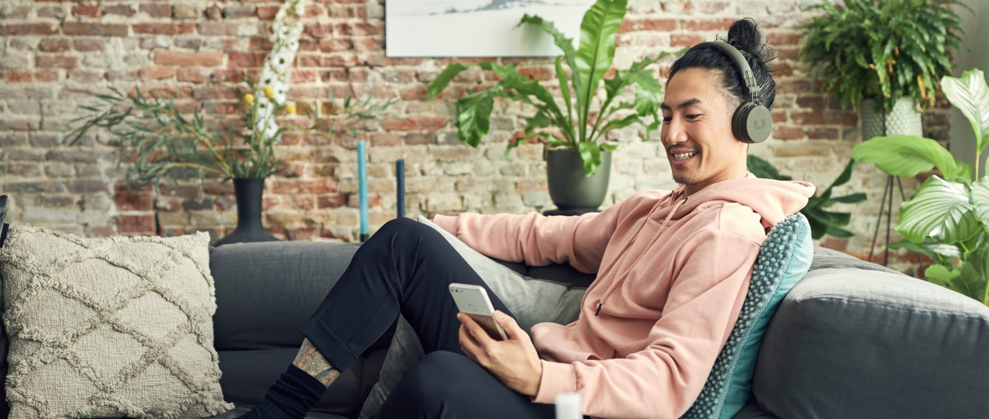 Mann auf dem Sofa hört sich Musik über eine Streaming-Plattform an