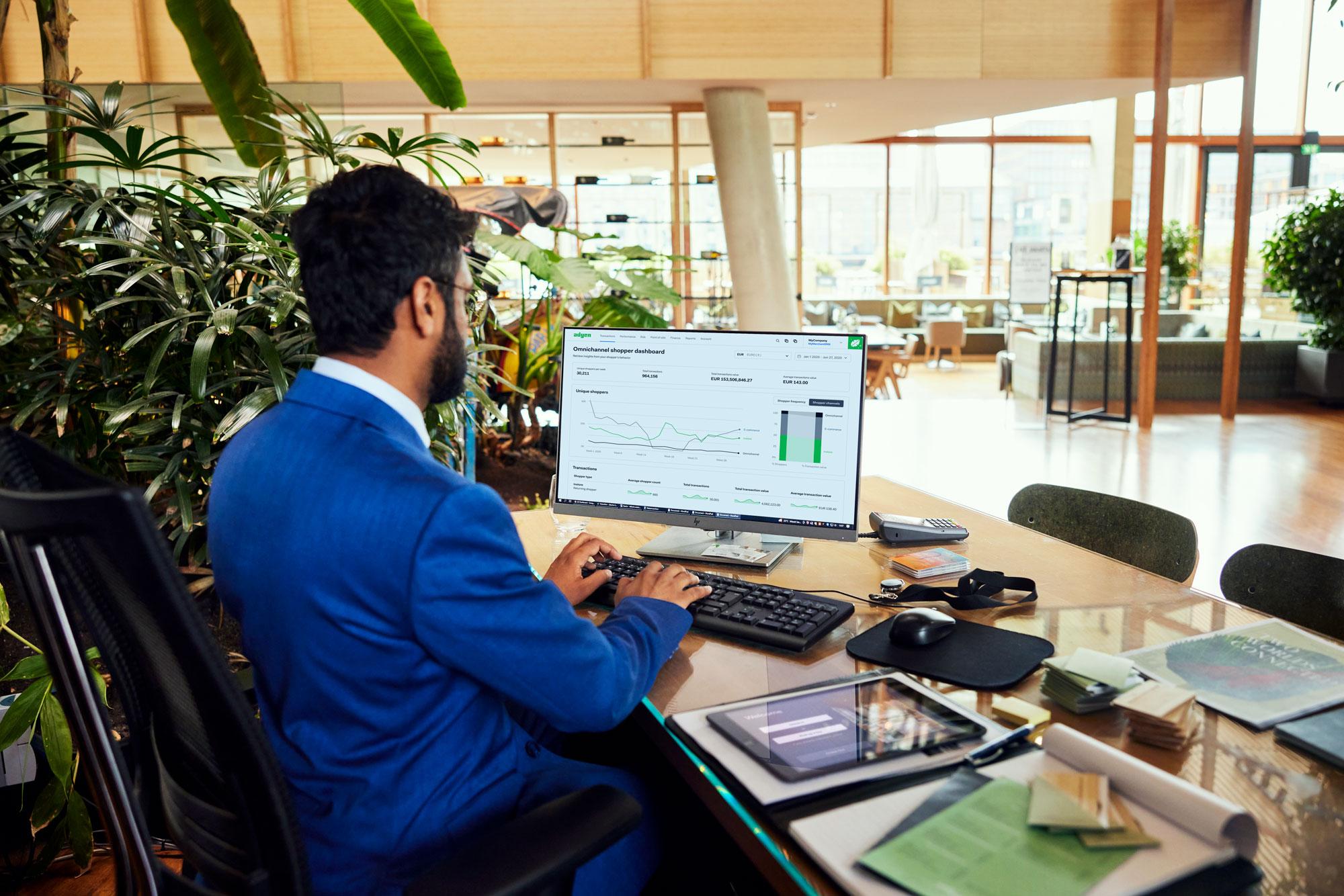 A hotel employee looking at a Adyen dashboard with data charts.
