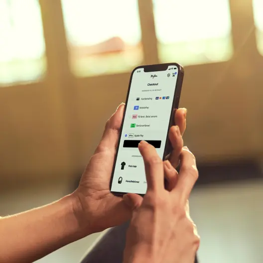 Primer plano de manos sosteniendo un smartphone que muestra las opciones de pago de checkout de Adyen.