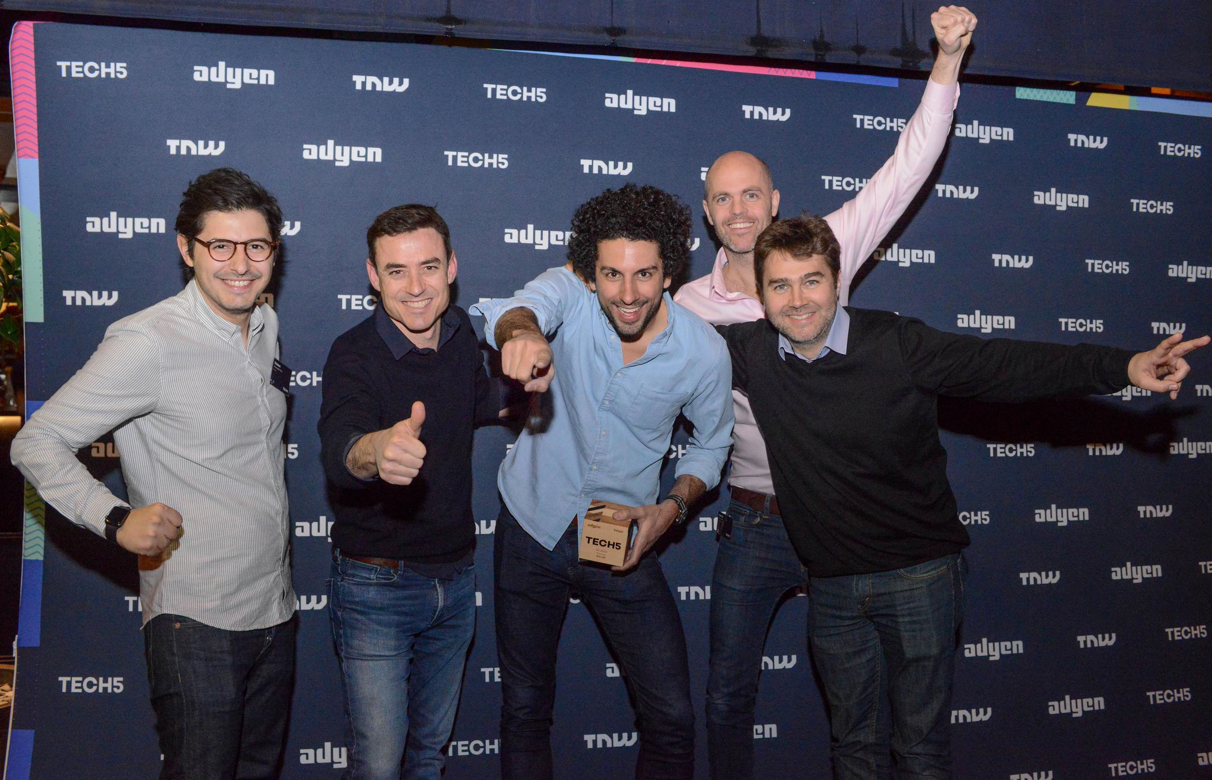 Groupe de cinq hommes souriants et posant avec un trophée lors d'un événement avec des fonds Adyen et TECH5.