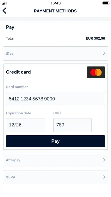 Mobile phone displaying a payment screen with credit card input fields and payment methods including Adyen options.