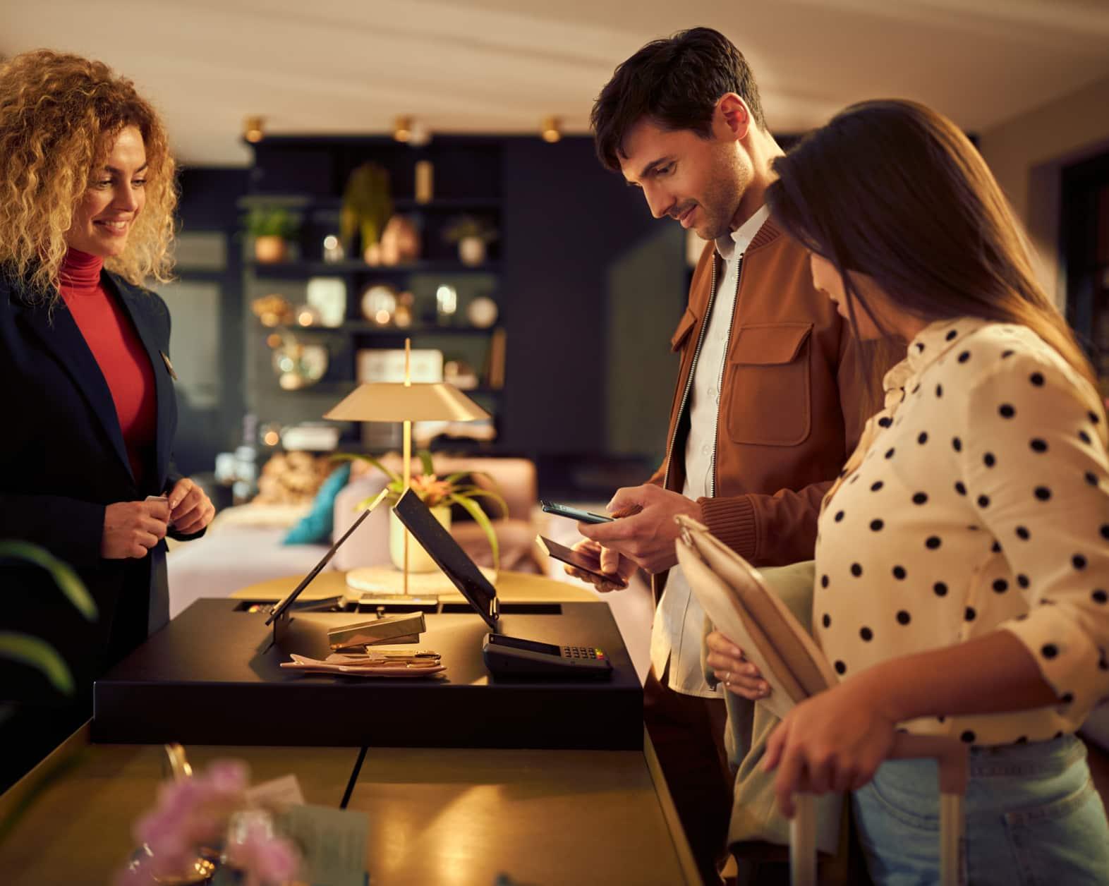 Clientes realizando el pago en el mostrador de recepción de un hotel con pago móvil.