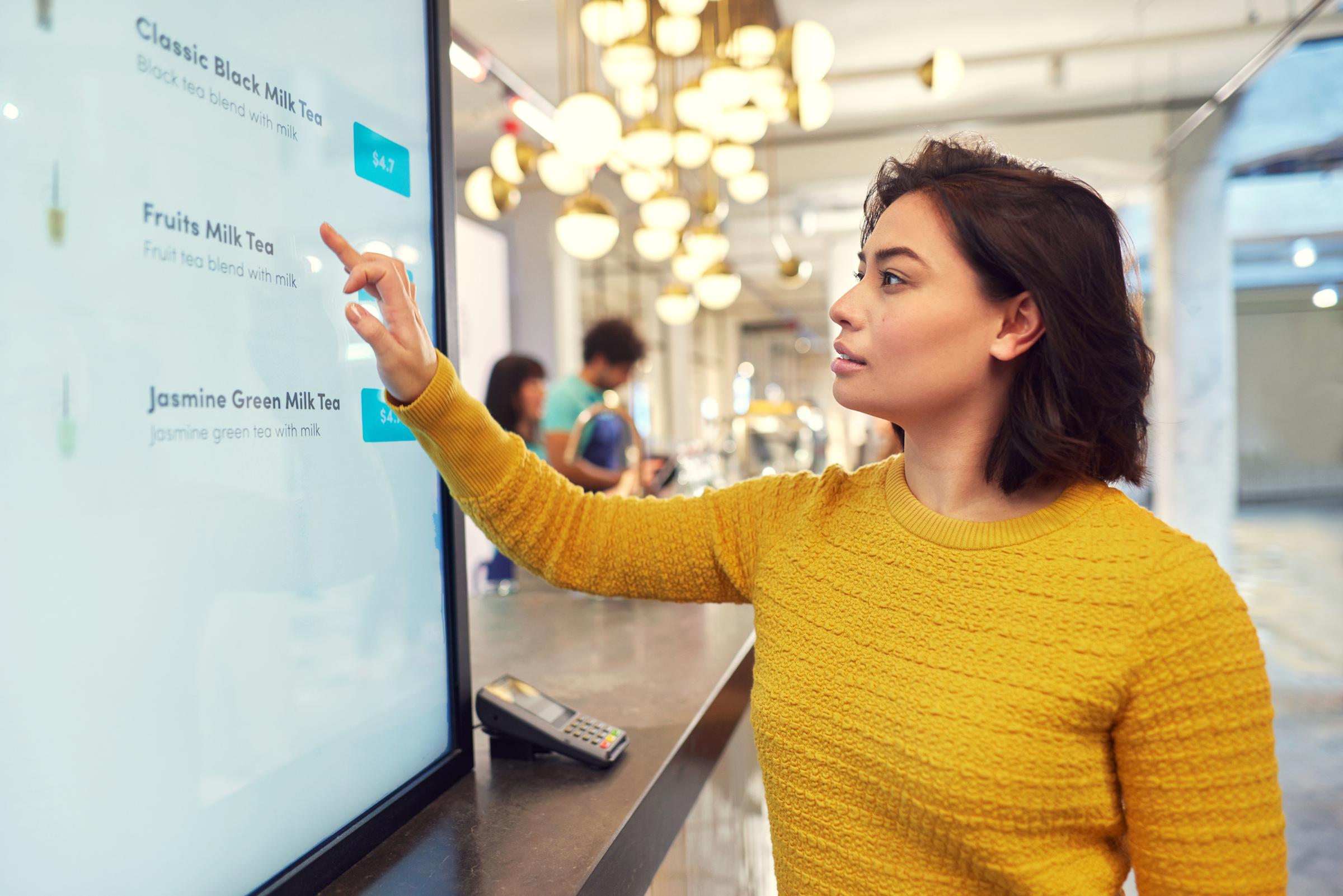 Woman ordering a smoothie via a self-service kiosk.
