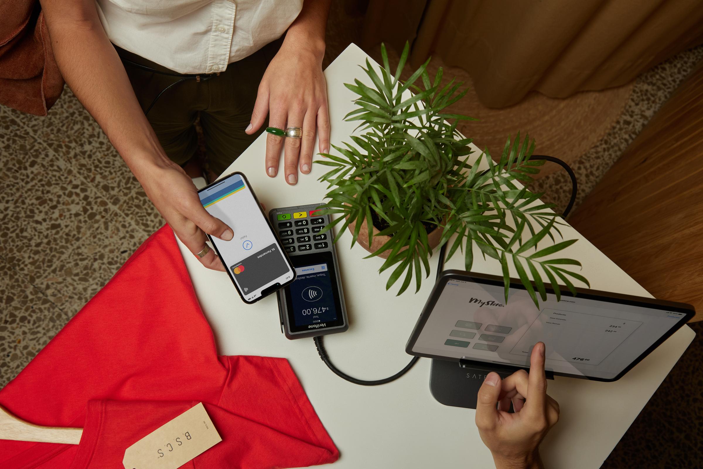 Persona che utilizza un telefono cellulare per effettuare un pagamento senza contatto su un terminale di pagamento Adyen