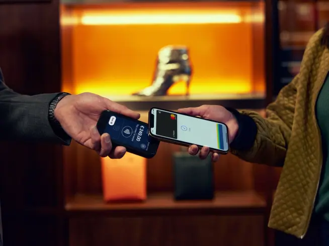Two people making a contactless payment using smartphones with Adyen interface.