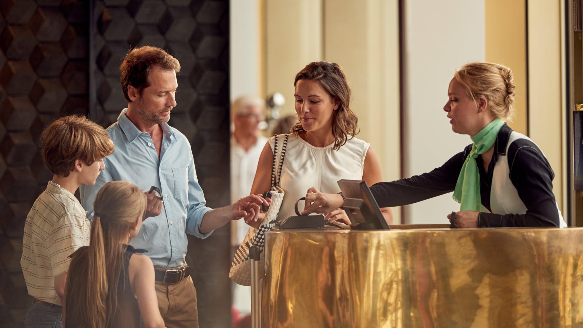 Familie som sjekker inn på hotellresepsjonen med en ansatt som hjelper