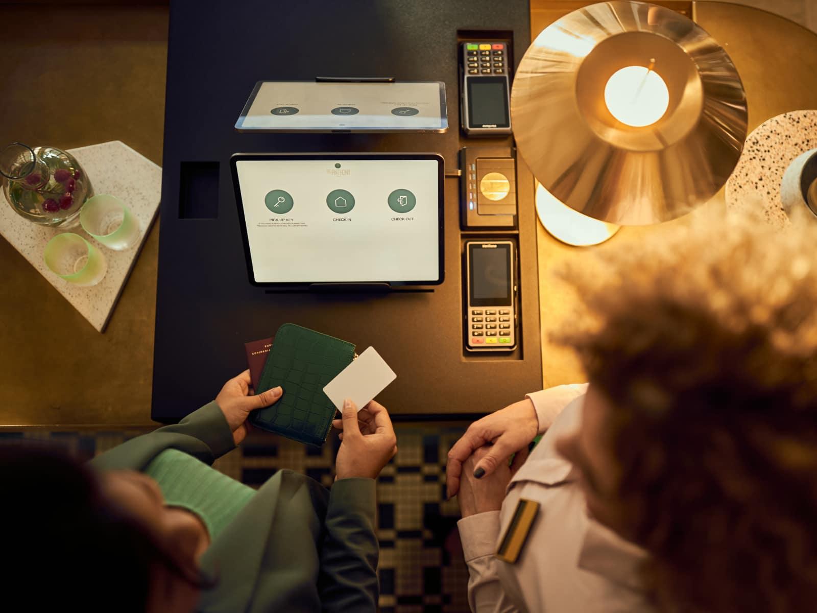 Two people at a bar with an Adyen payment terminal showing options such as 'pick up', 'dine in'.