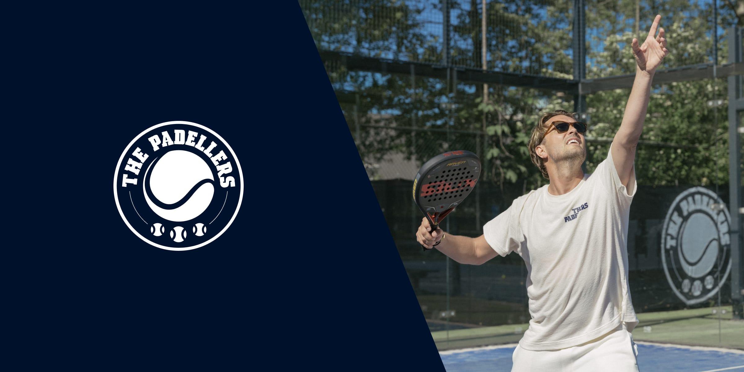 Man speelt padel met 'The Padellers' logo zichtbaar op zowel zijn shirt als de muur van de baan.