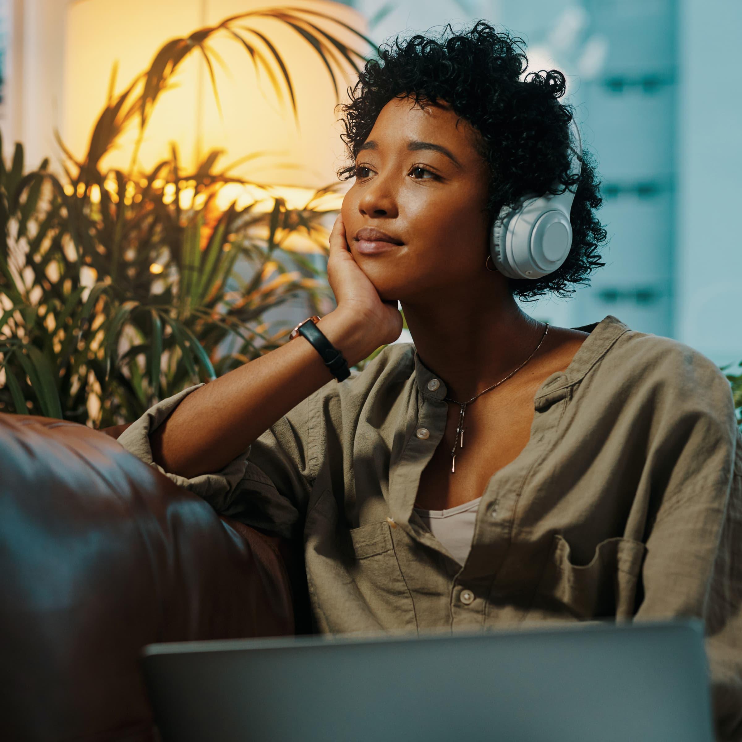 A woman on a couch listening to music on headphones.