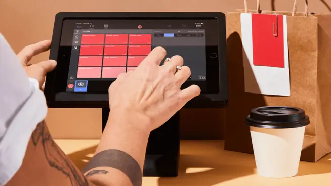 Person using a tablet displaying Adyen's point of sale interface with items and prices.