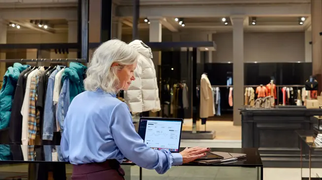 Retail employee using Adyen's payment system on a laptop in a clothing store.