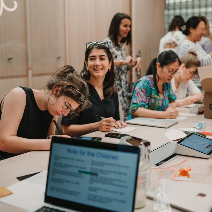 Group of people in a workshop setting with laptops and mobile devices.