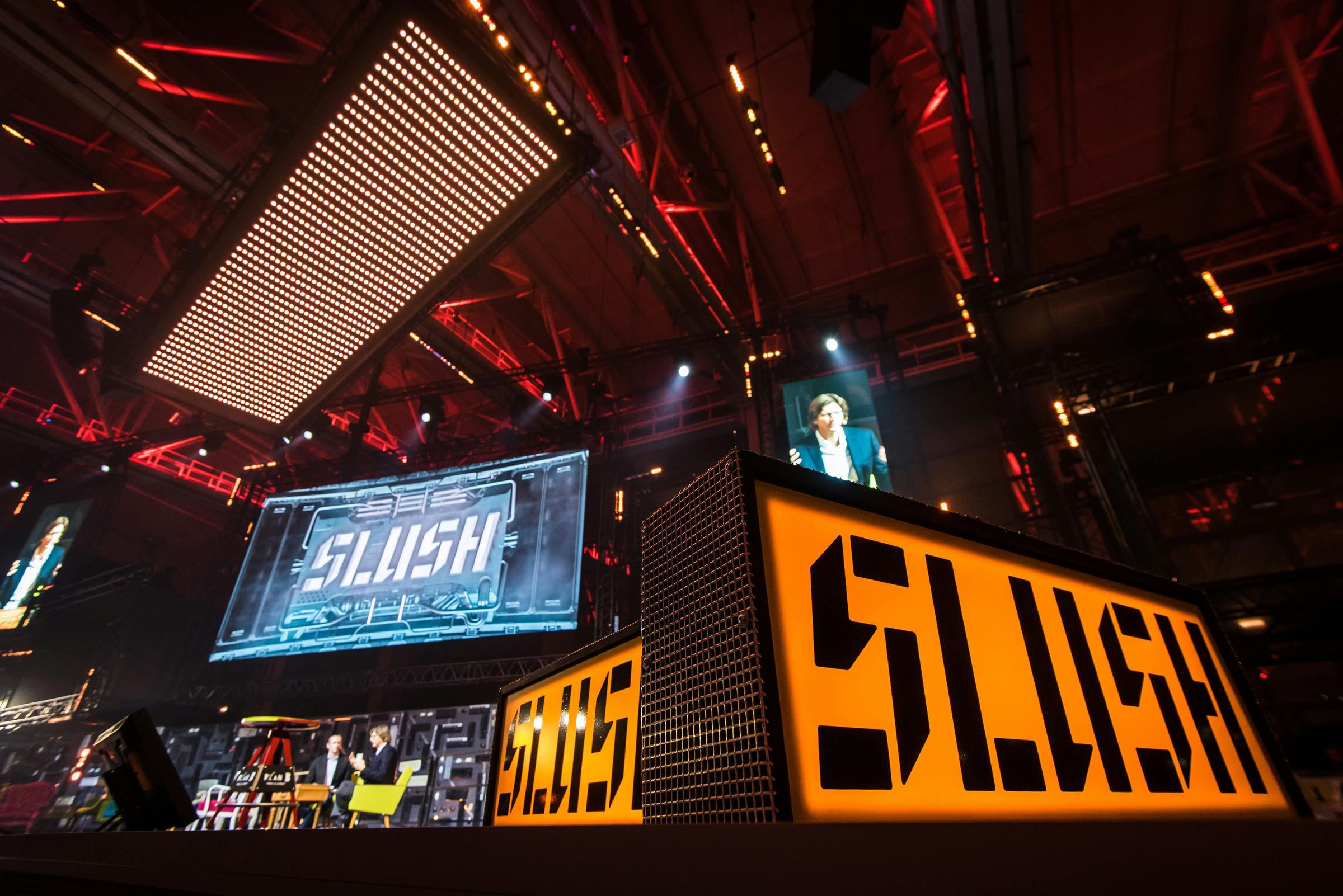 Speakers discussing on stage during Slush event in Helsinki, Finland.
