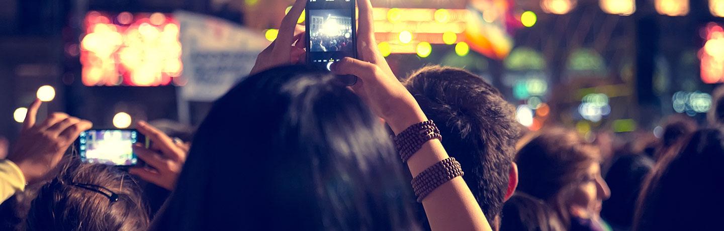Crowd of people capturing an event on their smartphones at night.