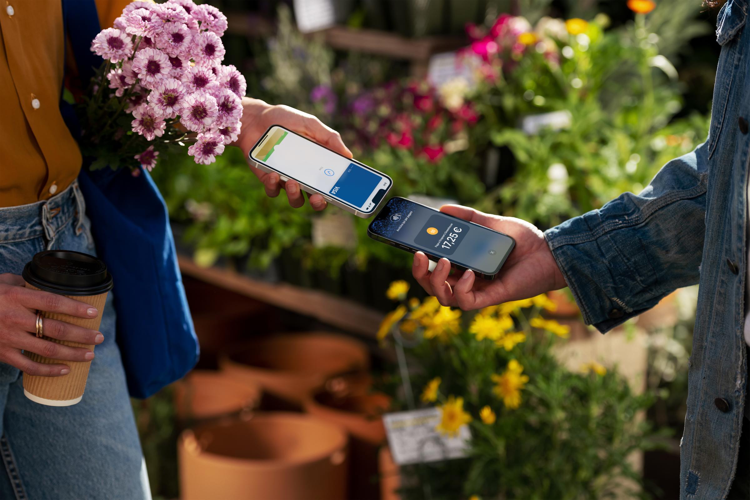 A customer in an Italian flower shop tapping their iPhone at the seller's iPhone to pay for the purchase.