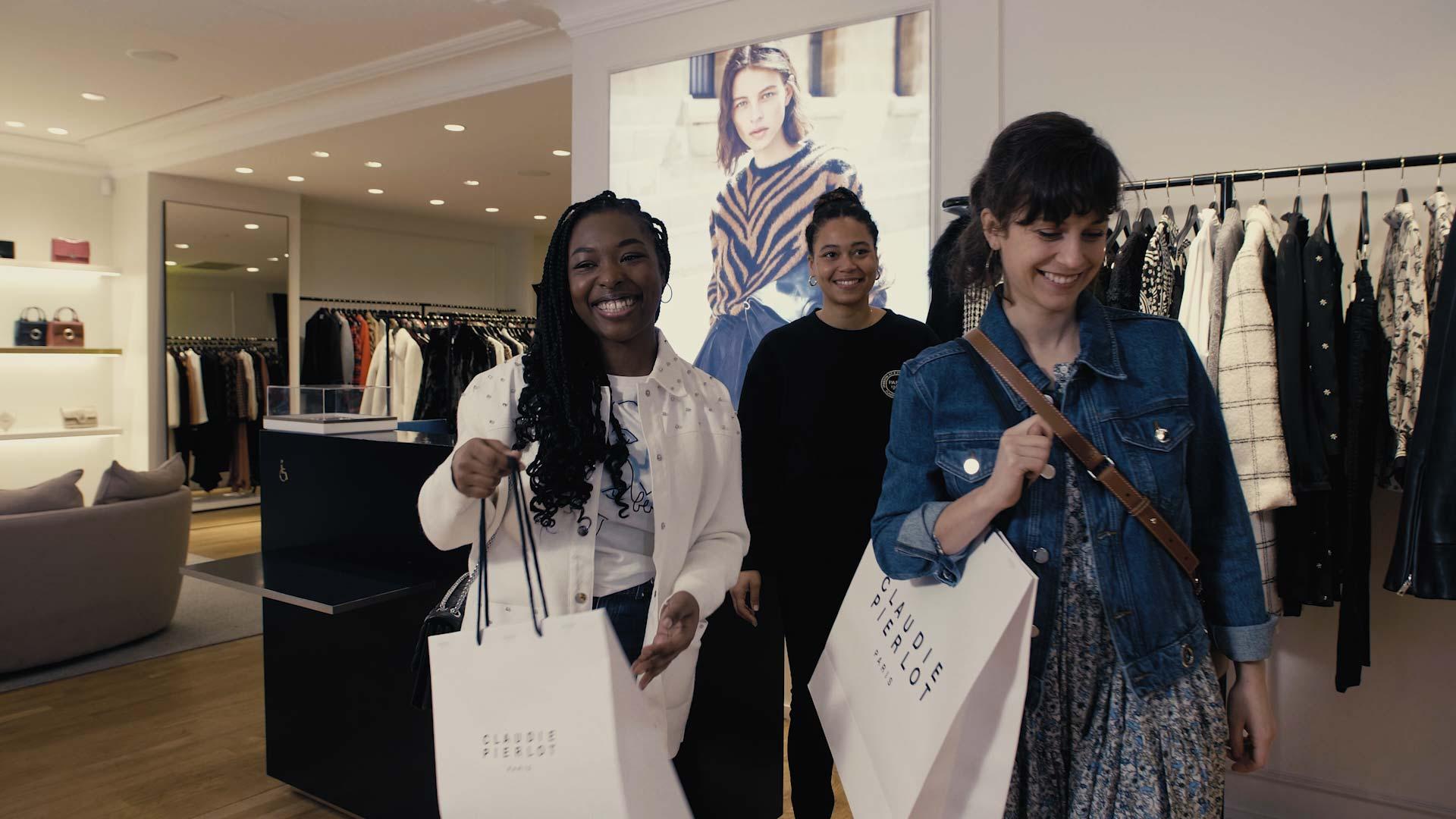 Three happy women holding shopping bags in a clothing store.