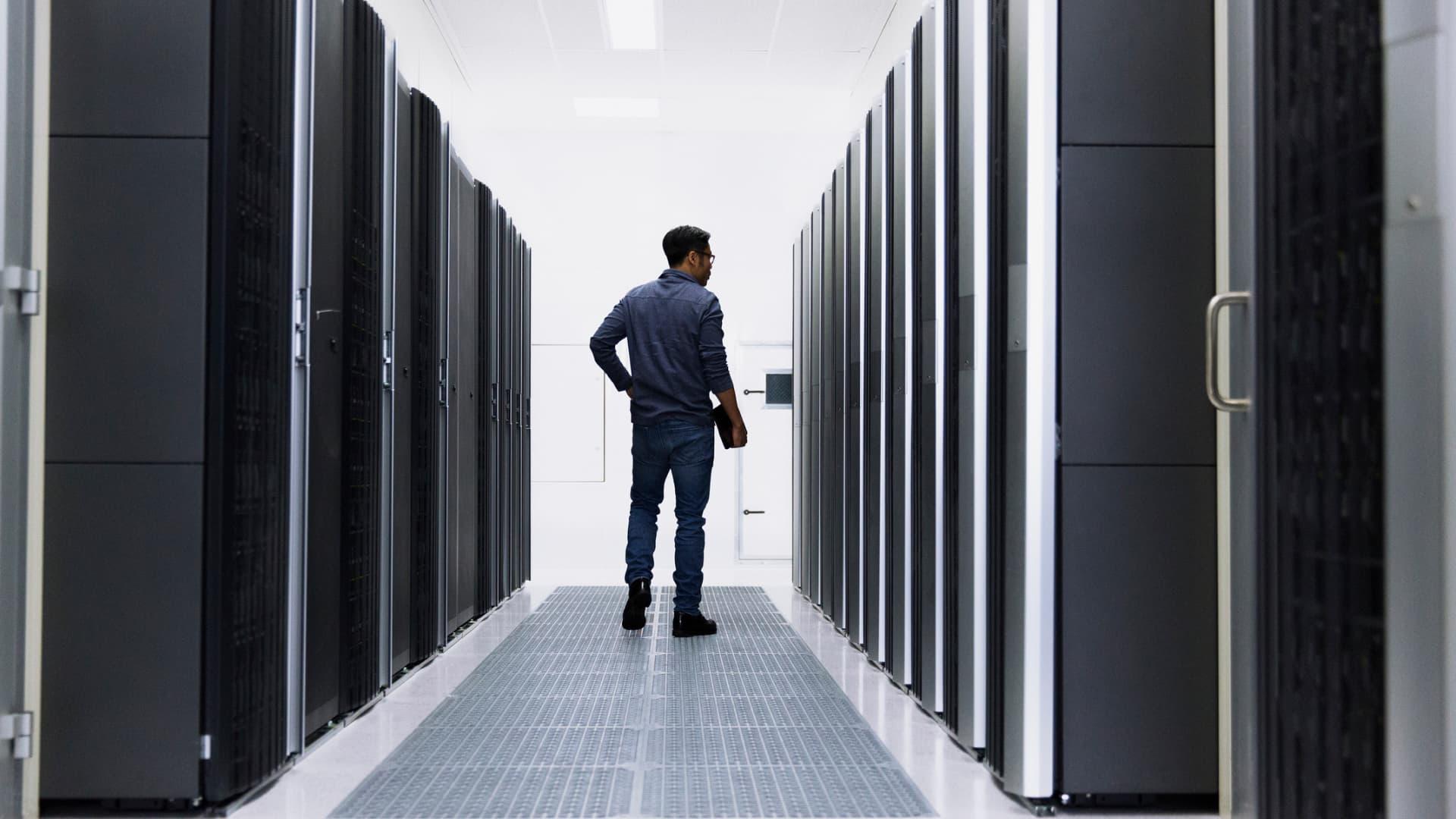 Man standing in a data center aisle between server racks.