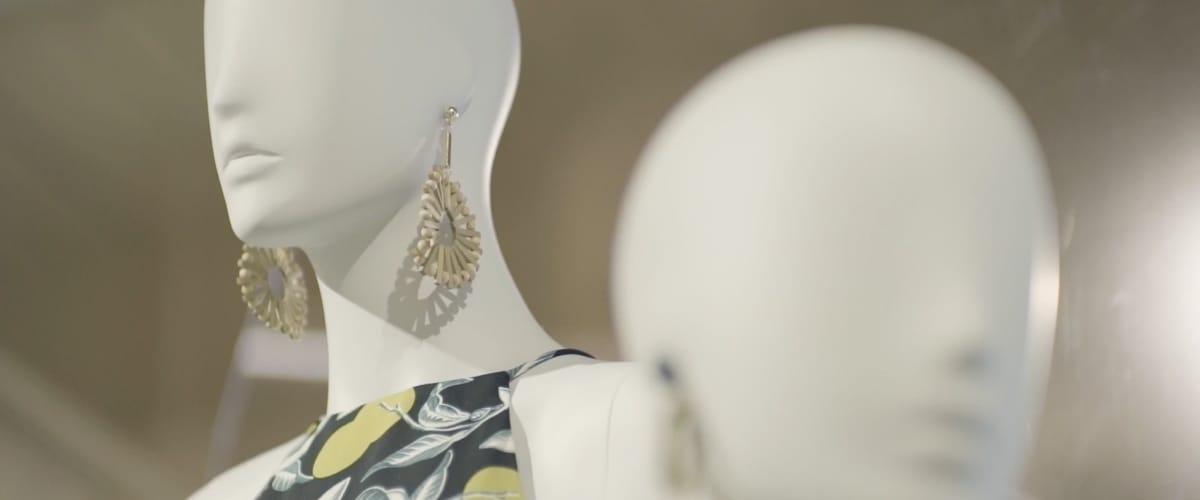 Close-up of mannequins with one wearing earrings and a patterned dress.