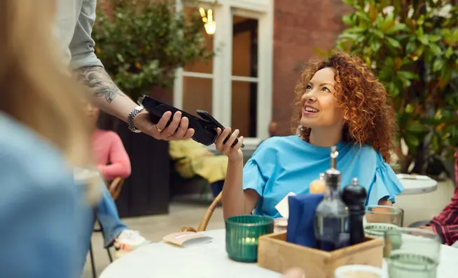 Customer making a payment using a portable card reader at a restaurant.