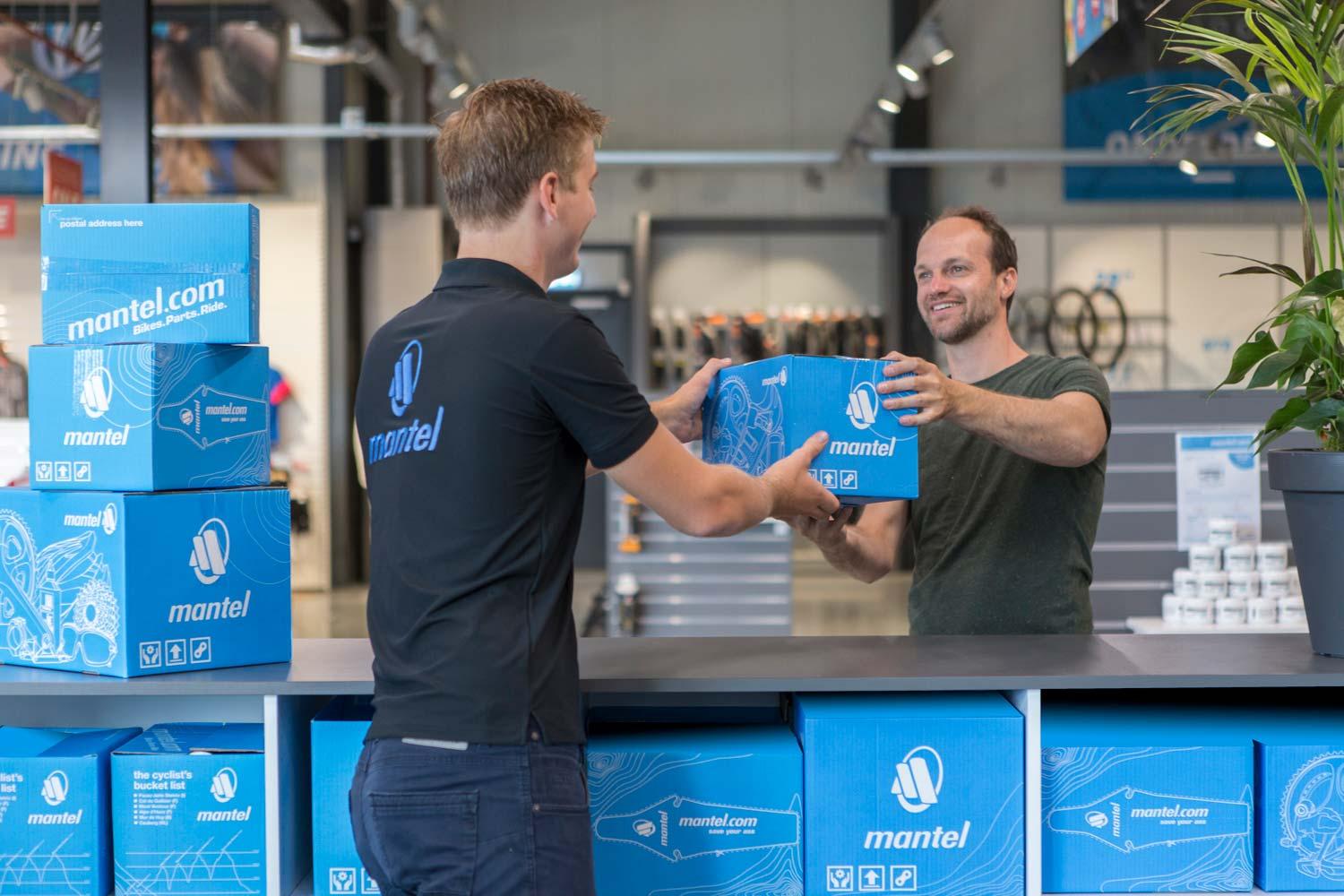 Twee mannen wisselen een verpakt product over een toonbank.