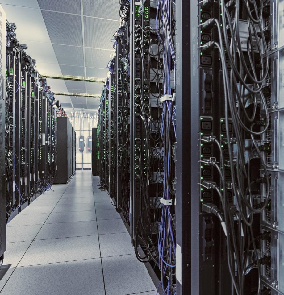 Rows of server racks with network and power cables in a data center.
