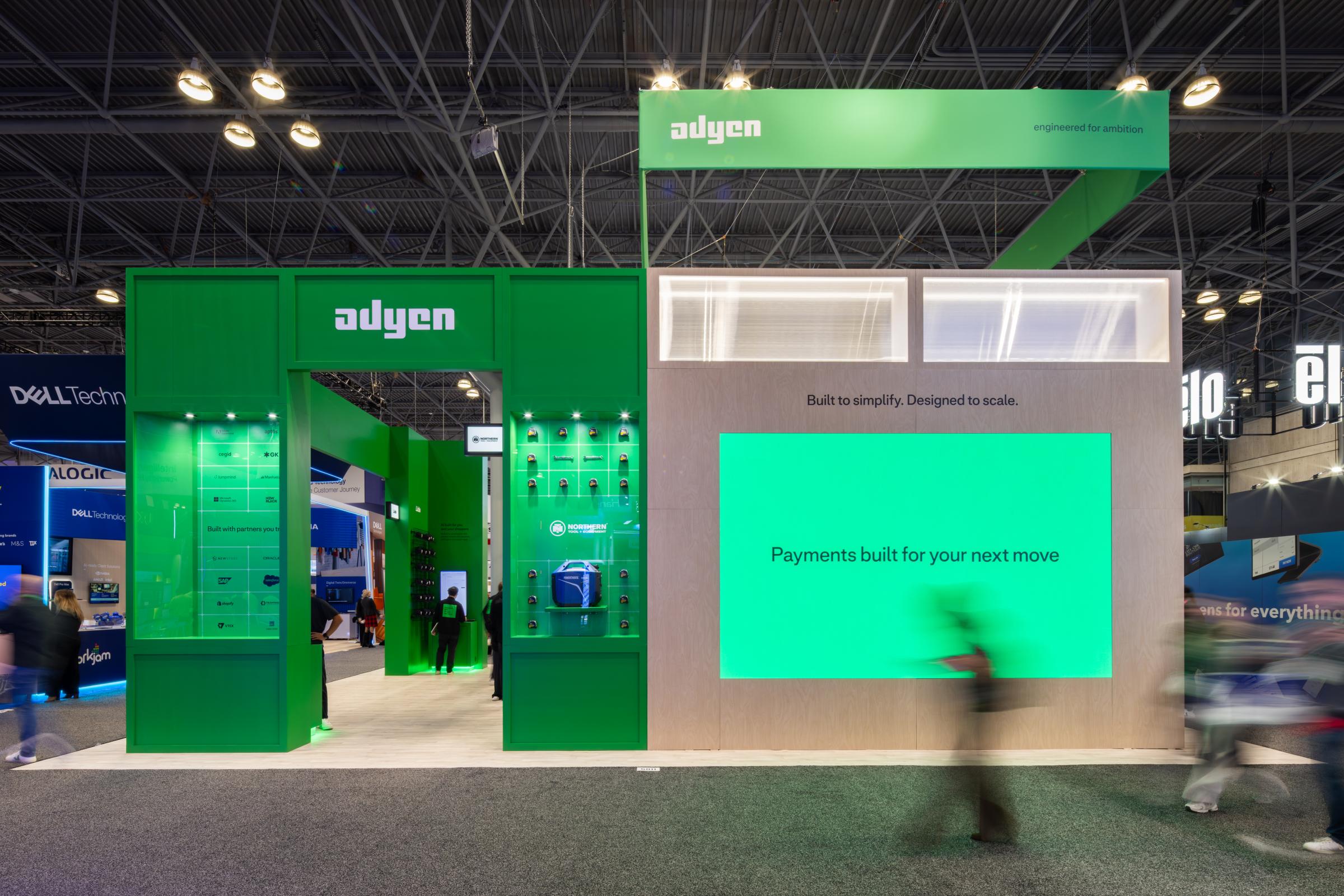 Adyen booth at an event showcasing payment solutions with digital displays and branding.