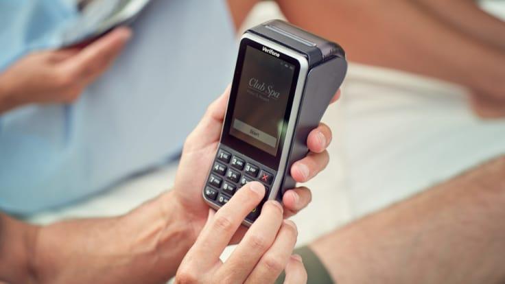 Pessoa segurando um terminal de pagamento por cartão