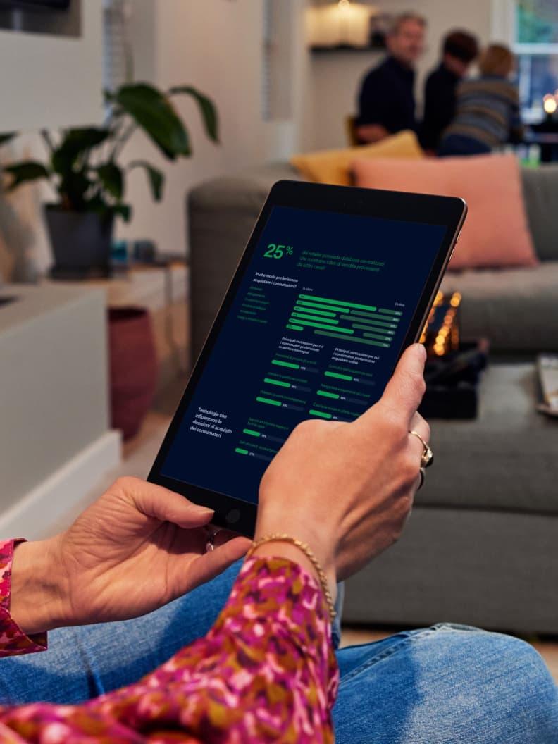 Pessoa sentada e a segurar um tablet que exibe o painel de análise da Adyen com gráficos.