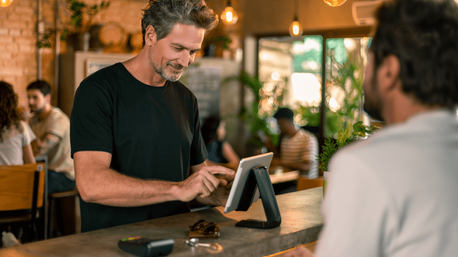 Um homem usando um terminal de ponto de venda Adyen para transação em um café