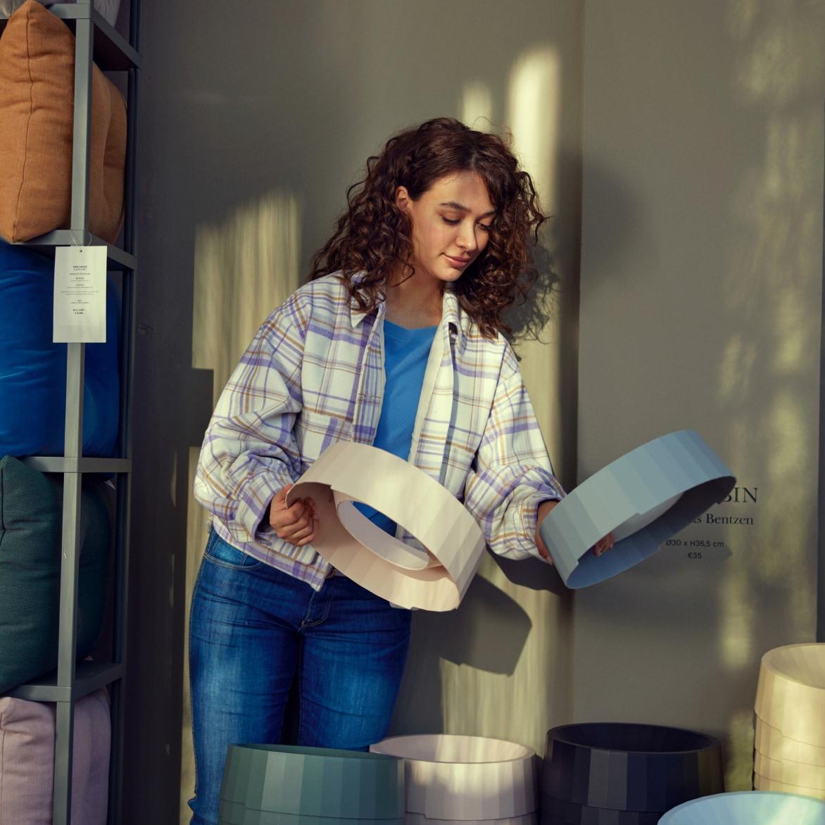 A person examining two circular box lids in a retail setting with shelving and various products.