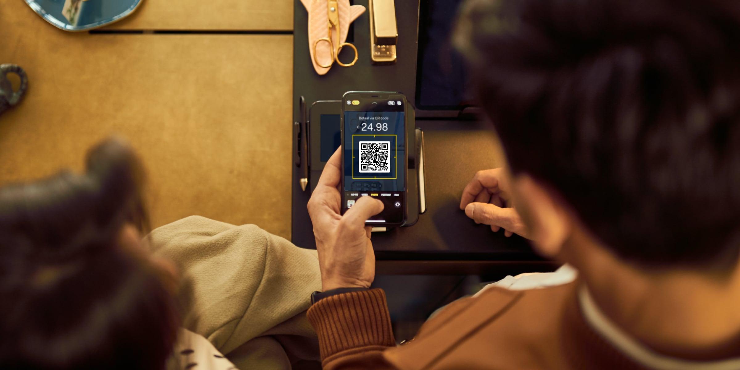 Persona che utilizza un dispositivo portatile per scansionare un codice QR per il pagamento