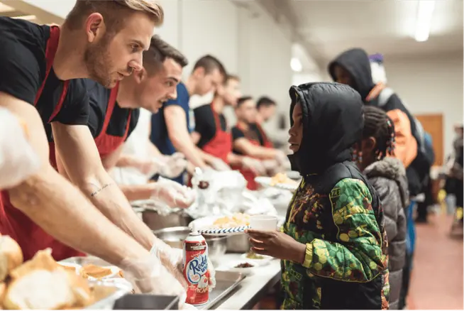 Volunteers serving food to people at a community shelter