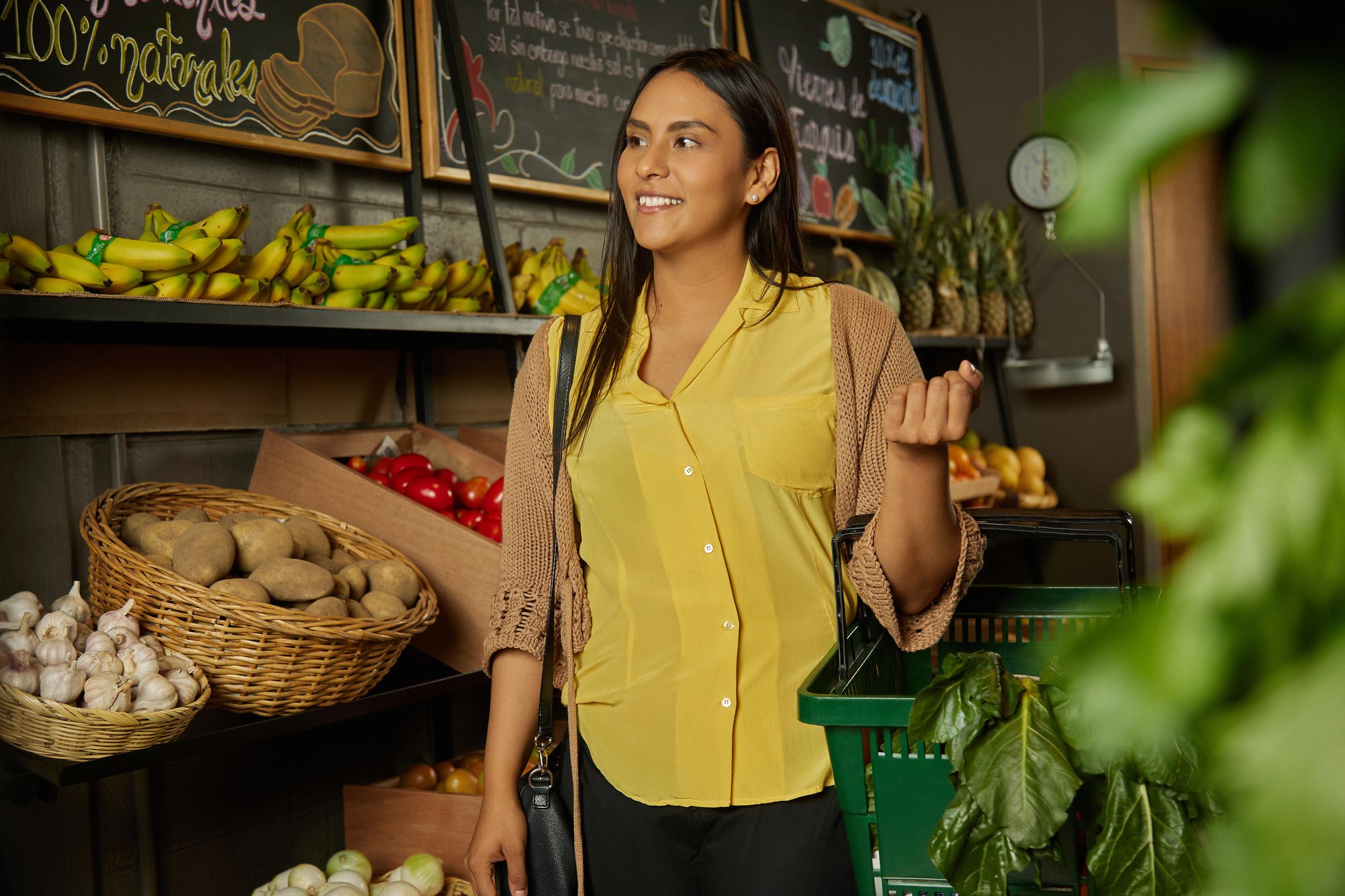 Smiling woman shopping for fresh produce at a grocery store.