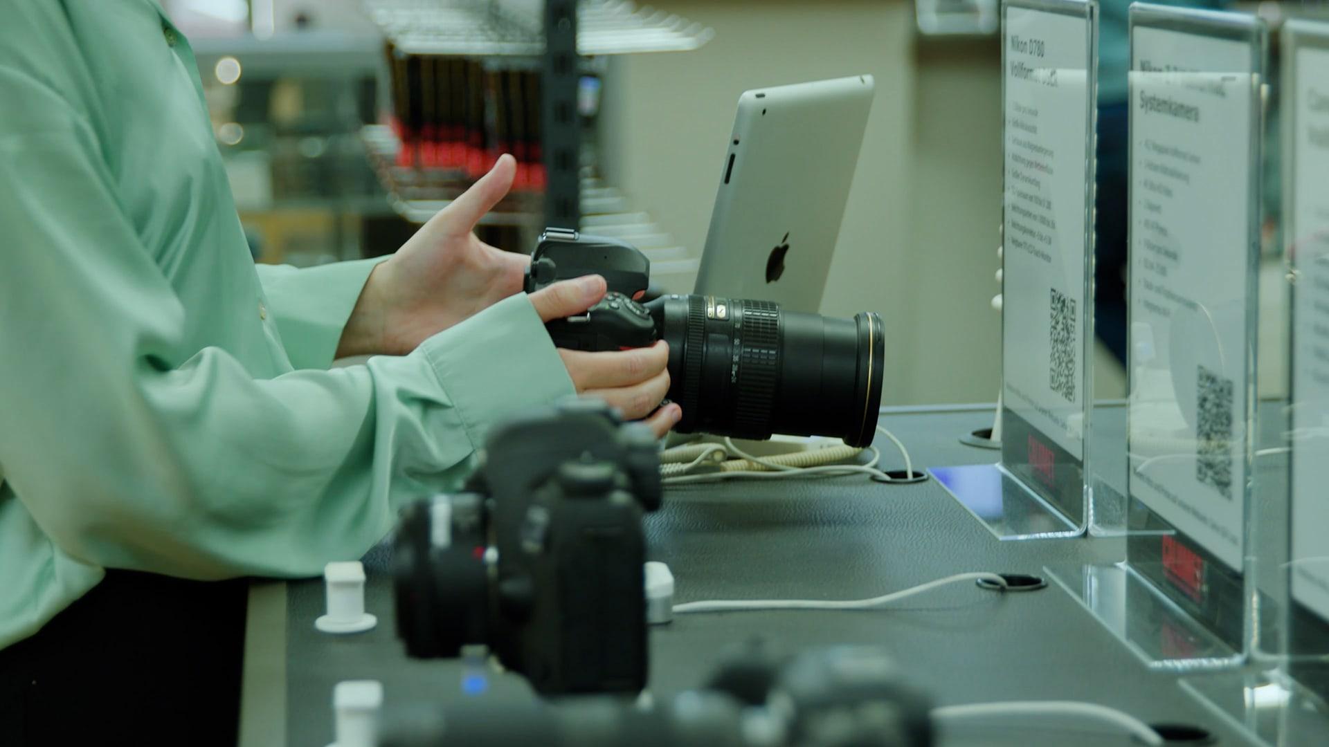 Person untersucht eine Kamera neben Geräten mit Adyen QR-Code-Zahlungsoptionen