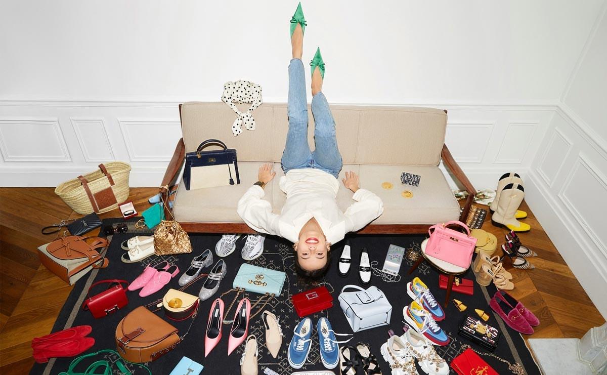 Person lying upside down on a couch surrounded by assorted fashionable items.