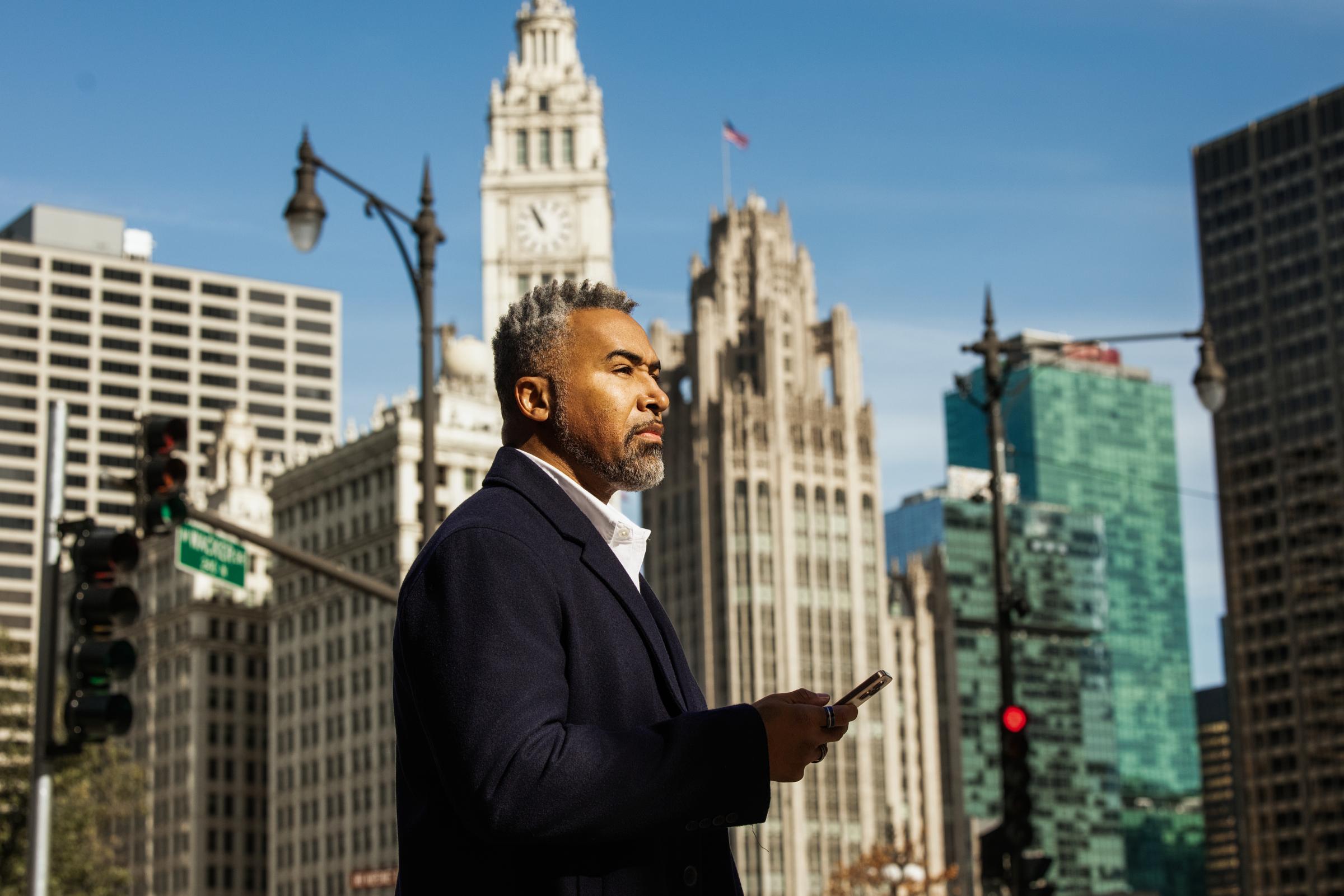 Business professional using a mobile device in an outdoor urban setting with skyscrapers.