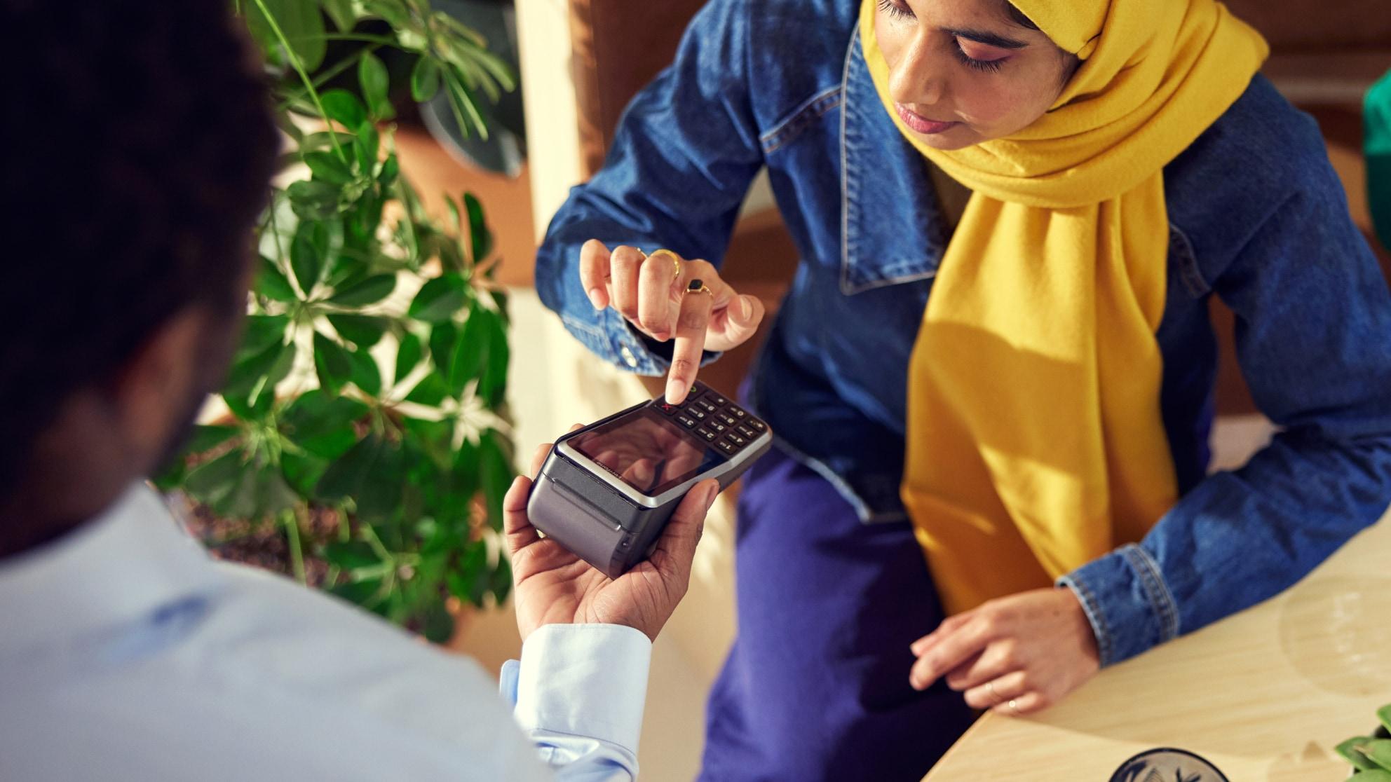 Klient wykonujący płatność przy użyciu terminala Adyen trzymanego przez pracownika