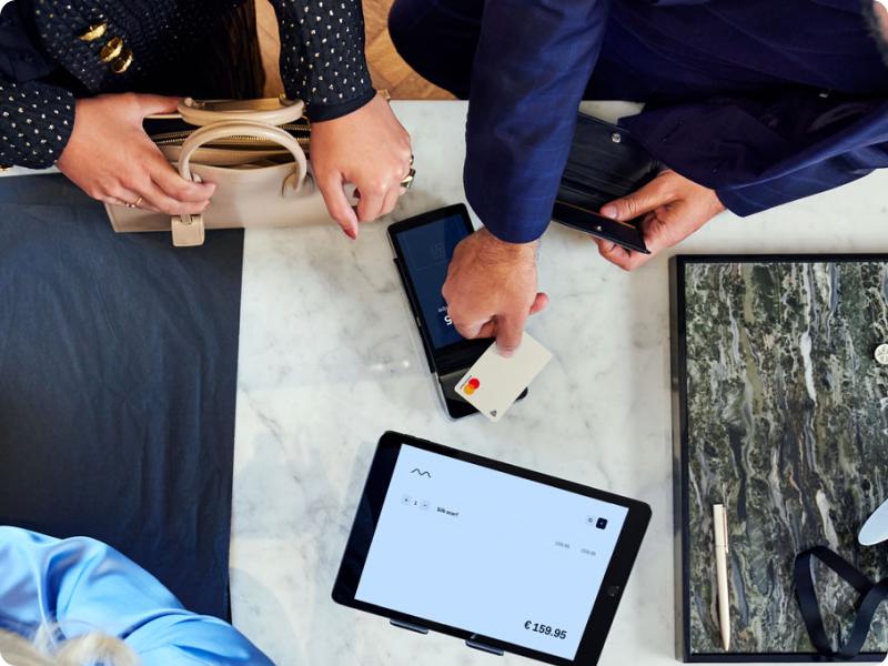 Customer paying via contactless card on an Adyen payment terminal with a tablet displaying the transaction.