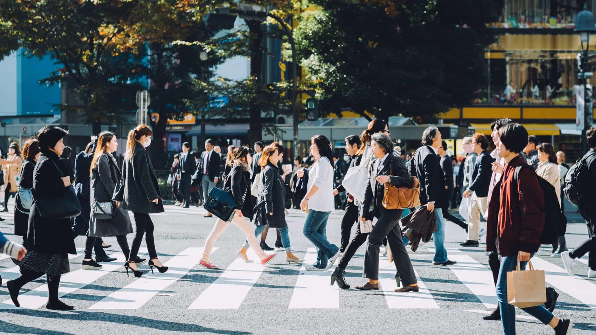 Crowd of people crossing the street on a sunny day.