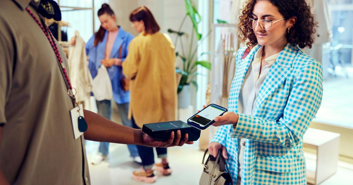 Customer using a mobile phone to make a contactless payment on a portable card reader.