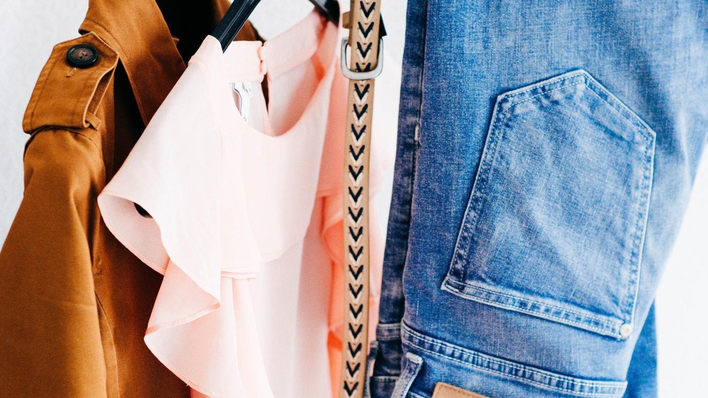 A selection of clothing items including a brown coat, pink blouse, and blue jeans.