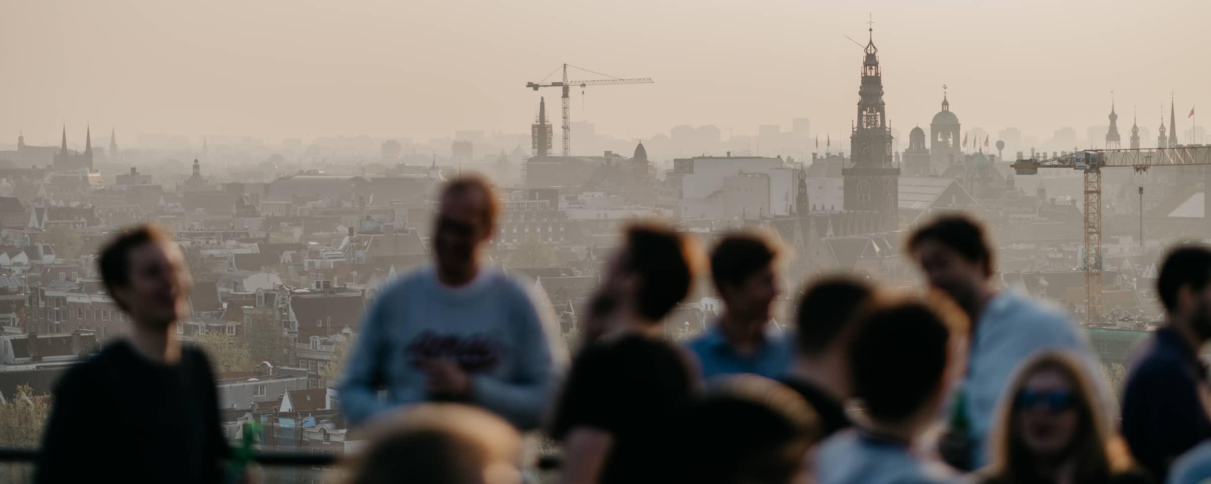 People gathered with a city skyline in the background at dusk.