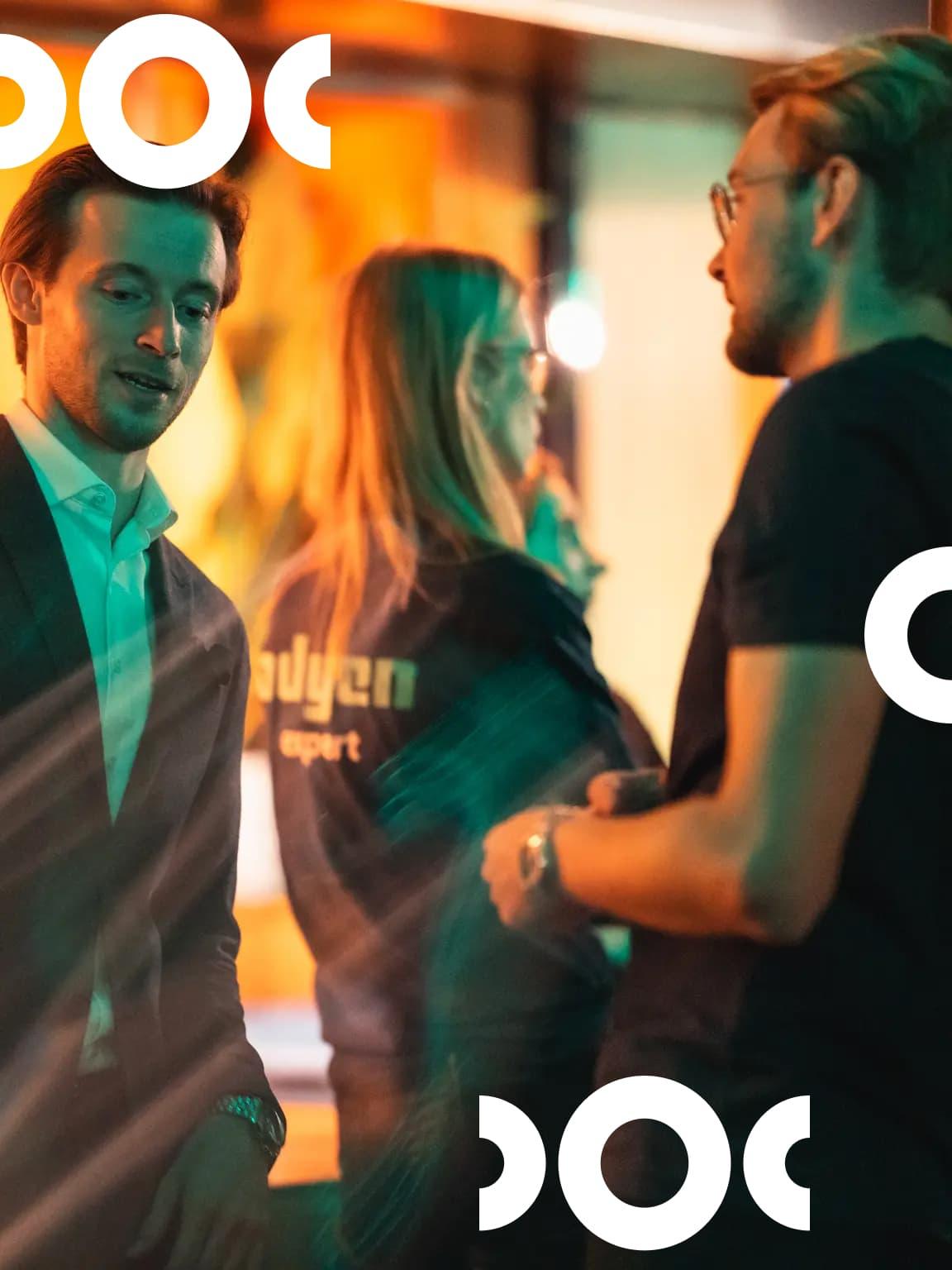 Event attendees chatting, with Adyen Experience branded elements.