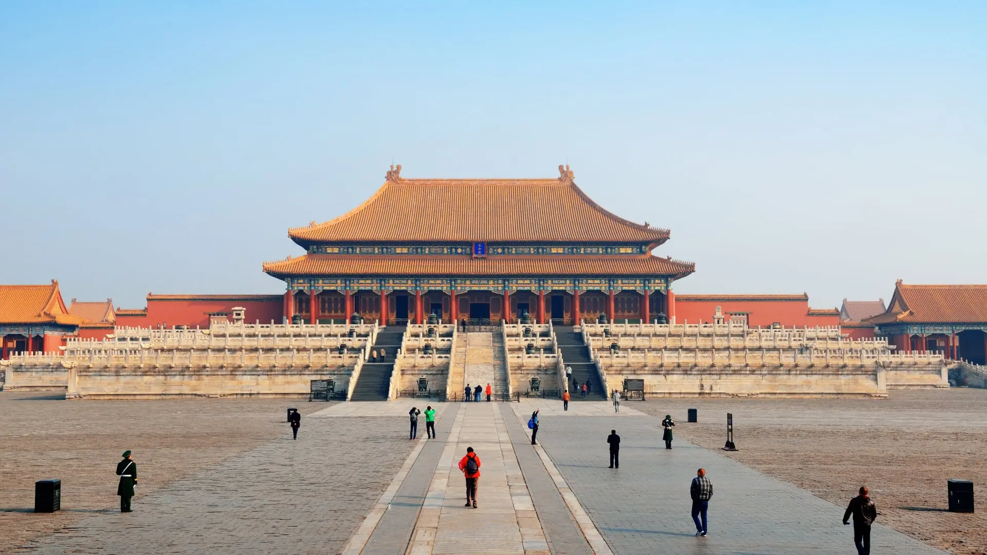 Visitors walking in the courtyard of the Forbidden City under a clear sky in China.