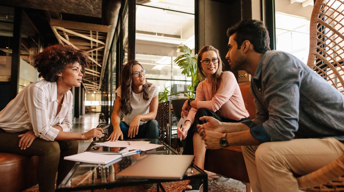 Quatro colegas em discussão em um ambiente de escritório moderno