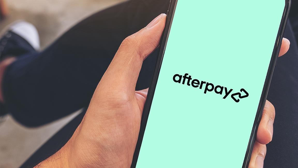 Close-up of a hand holding a smartphone displaying the Afterpay logo.